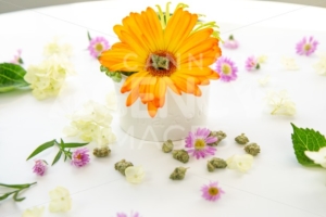 Bright Orange Gerbera Daisy Floral Arrangement in Ceramic Dish with Words Baked with Cannabis Buds and Marijuana Nug on White Table – Cannabis Wedding - The Cannabiz Agency