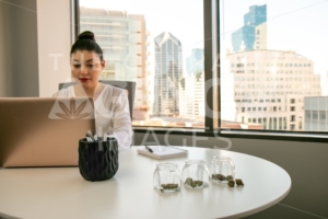 Female Cannabis Entrepreneur working on Marketing for Marijuana Business in Bright, Soft Lit Office - The Cannabiz Agency