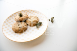 High Angle on a Yellow Patterned Plate with Chocolate Chip Cookies and Marijuana Buds - The Cannabiz Agency