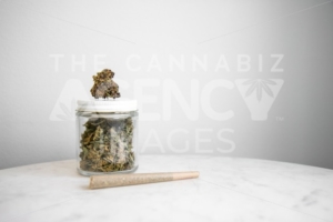 Joint, Bud and Cannabis Glass Jar on White Marble – Cannabis Dispensary Products - The Cannabiz Agency