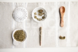 Marijuana Product Neatly Laid Out on Surface. Buds, Joint, Flower, Ground Cannabis, Wooden Spoon, Bowl – Top Down – Minimalist Cannabis - The Cannabiz Agency