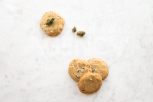 Top Down View on White Marble of Edible Marijuana Chocolate Chip Cookies and Buds - The Cannabiz Agency