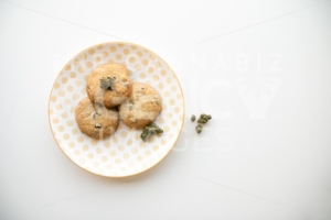Top Down on Yellow Patterned Plate with Chocolate Chip Cookies and Marijuana Buds - The Cannabiz Agency